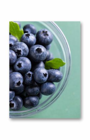 Micro close up of blueberries in glass bowl with copy space on green background
