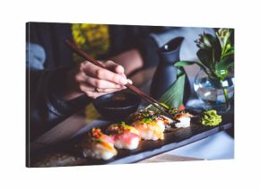 Man eating sushi set with chopsticks on restaurant