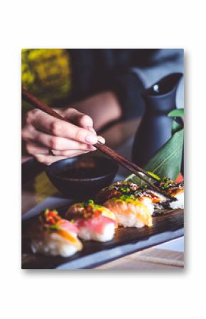 Man eating sushi set with chopsticks on restaurant