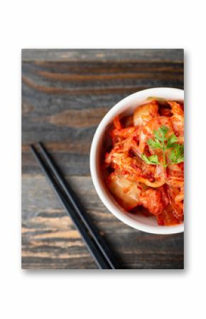 Kimchi cabbage in a bowl with chopsticks for eating on wooden background, top view, Korean food
