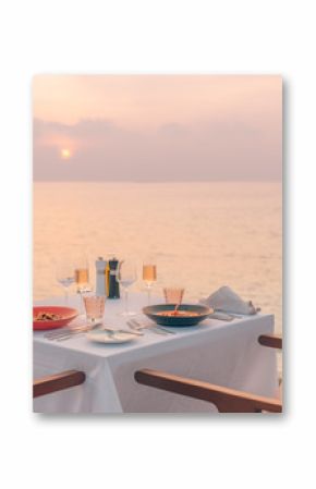 Romantic dinner on the beach. Wine glasses next to a beautiful dinner table setting, luxury resort hotel at beach view