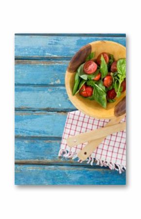 Fresh salad in wooden bowl by spoon and fork on table