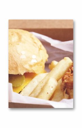 Takeout meal resting in box on table, with cheeseburger, pickles, fries, onion rings, copy space