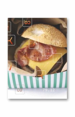 Showing cheeseburger with bacon in striped box on studio tabletop, with carbon footprint icons