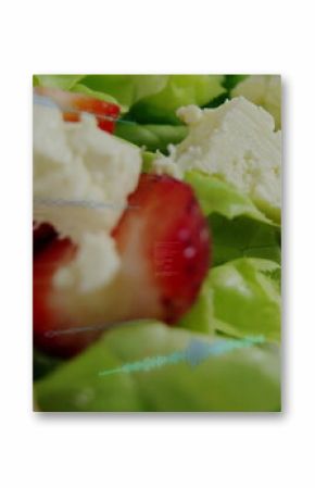 Salad featuring green lettuce strawberry slices, crumbled white cheese on plate, digital overlay