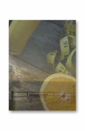 Still-life featuring bananas, carrots, orange halves, blueberries, tape and dumbbell on table