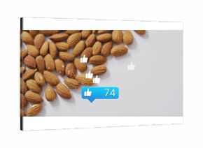 Cluster of almonds on white tabletop, showing thumbs-up icons and notification bubble, copy space