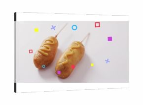Featuring two battered corn dogs resting on white table, with mustard drizzles and geometric shapes
