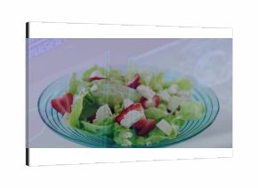 Displaying glass bowl containing butter lettuce, sliced strawberries, cheese cubes on kitchen table