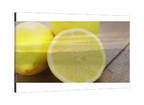 Displaying halved lemon revealing juicy pulp on kitchen tabletop, with two whole lemons