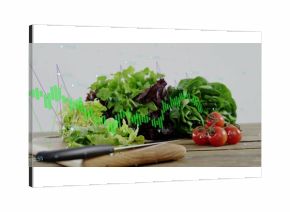 Displaying knife and lettuce on cutting board in kitchen, with cherry tomatoes and financial charts