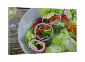 Showing salad bowl with lettuce, tomatoes, olives and basil on rustic table, with digital overlay