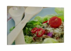 Displaying quinoa salad on pale blue plate on wood table, checkered cloth, crossed wooden spoons