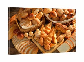 Variety of bread in wicker basket on old wooden background.