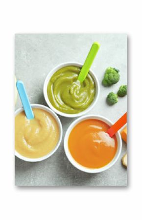 Bowls with baby food on grey background