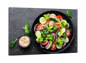 Healthy vegetable salad of fresh tomato, cucumber, onion, spinach, lettuce and sesame on plate. Diet menu. Top view.