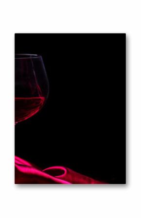Glass of red wine on red silk against black background. Wine list design background.