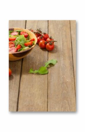 Fresh salad in bowl by cherry tomatoes on table