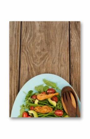 Fresh salad in blue plate on brown wooden table