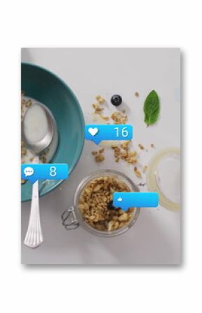 Displaying turquoise granola bowl with yogurt and berries on white surface, showing social icons
