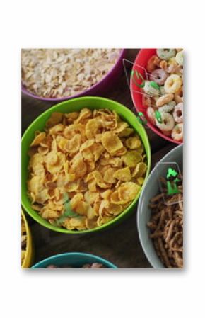 Displaying eight colorful cereal bowls lining wooden table, showcasing various cereal types