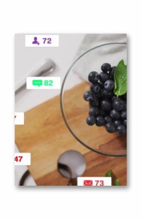 Blueberry bowl resting beside granola jar in kitchen, with social media reaction icons, copy space