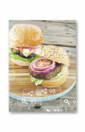 Displaying sesame bun burgers on wooden board with blue handle at picnic table, with media icons