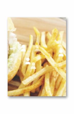 Displaying hamburger resting on wooden board with lettuce tomato red onion and seasoned fries
