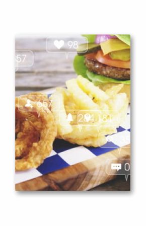 Board holding fried onion rings, fries, lettuce-wrapped burger at cafe table, with social icons