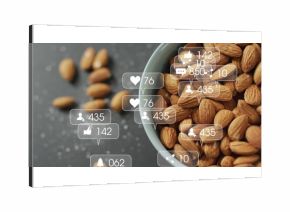Displaying ceramic bowl holding almonds on dark countertop, with social media icons, copy space