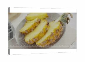 Displaying fresh pineapple slices on grey plate on wooden table, with blueberries in container