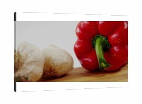 Displaying red bell pepper resting with garlic bulbs on board in kitchen with overlay, copy space