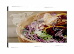 Wooden bowl sitting on table with greens, sprouts, microgreens, root veggies over world map overlay