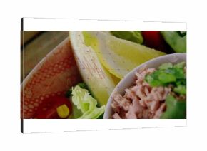 Displaying shredded tuna and lettuce in bowl on table, with herbs, cherry tomatoes, corn kernels