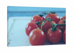 Cluster of cherry tomatoes sitting on white board at kitchen counter, with green stems and droplets