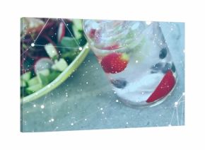 Showing glass holding iced fruit-infused water mint beside salad bowl on stone tabletop, copy space