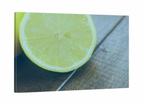 Showing halved lemon revealing juicy segments on wooden table, with whole lemon behind, copy space