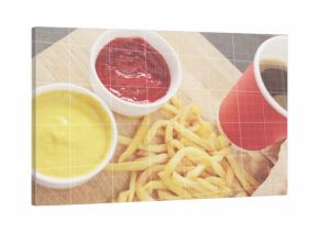 Displaying centered pile of thin French fries on restaurant table, with white ramekins and red cup