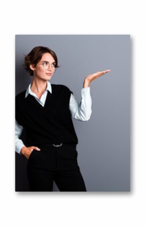 Photo of dreamy cute lady clerk dressed black vest eyewear looking showing arm empty space isolated grey color background