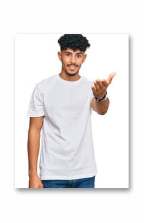 Young arab man wearing casual white t shirt smiling friendly offering handshake as greeting and welcoming. successful business.