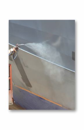 worker painting ship hull using airbrush gray paint