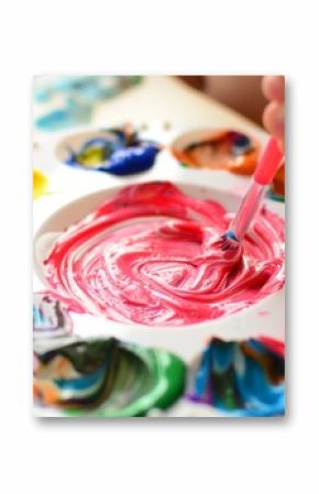 Child mixing paint on a palette of colorful paint