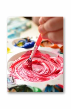 Child mixing paint on a palette of colorful paint