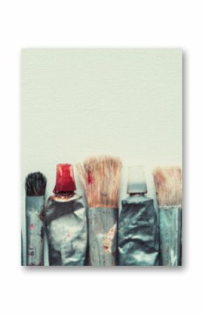 Row of artist paintbrushes and paint tubes closeup on artistic canvas background, retro stylized. Copy space for text.