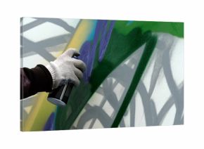 The artist's hand with a paint balloon draws graffiti on a white wall.