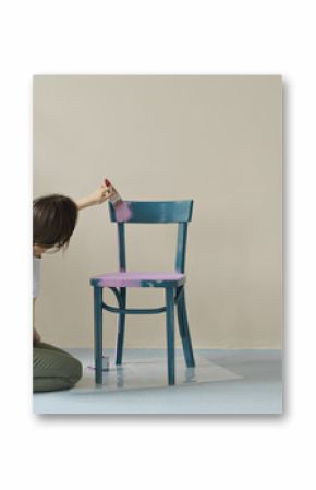 young woman painting chair in pink at home