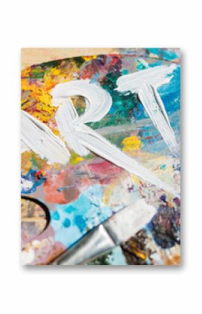 Word art painted with white gouache on colorful palette with paintbrush near by