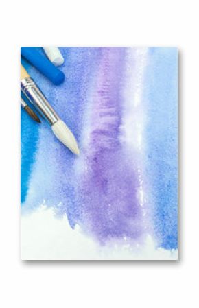 paintbrushes with paint and pastel crayons on blue watercolor background with paper texture