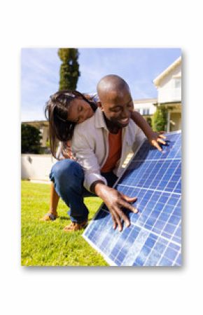 Outdoors, diverse father and daughter examining solar panel together