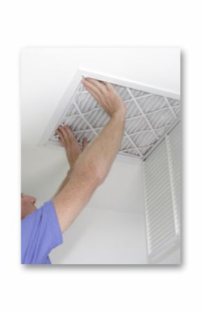 New Air Filter in Ceiling  Male pushing a clean air filter into place in the ceiling with both hands. One fresh furnace air filter being secured in the intake grid of the white home ceiling.  